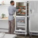 A man standing in front of a ServIt holding cabinet with clear doors.