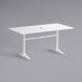 A white Lancaster Table & Seating dining table with a metal base and umbrella hole.