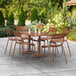 A Lancaster Table & Seating brown aluminum outdoor dining table with 6 chairs on a patio.