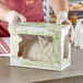 A person wearing gloves holding a Southern Champion bakery box with a bunny inside.