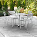 A white Lancaster Table & Seating outdoor table and chairs on a patio.