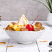 A bowl of vanilla soft serve with fruit and a cherry.