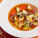 A bowl of College Inn beef bone broth with vegetables and herbs.
