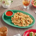 A green Acopa Foundations melamine oval platter with fried calamari, pasta, and dipping sauce on a table.