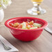 A red bowl of fruit on a table.