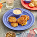 A purple Acopa Foundations melamine plate with food and a blue bowl of sauce on a table.