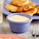 A blue ramekin filled with white sauce on a plate of food.