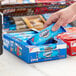 A hand holding a blue package of Nabisco Oreo cookies.