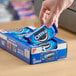 A hand putting a package of Nabisco Oreo cookies in a box.