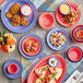 A table set with Acopa Foundations purple melamine plates and bowls of salad, yellow liquid, red soup, and white sauce.