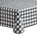 A black and white checkered Choice vinyl table cover with umbrella opening on a table.