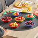 A tray with Acopa Foundations assorted color melamine fruit dishes filled with a variety of fruit on a table.