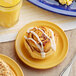 A plate of cinnamon rolls on a table with a glass of yellow liquid.