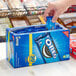 A hand putting a blue Nabisco Oreo cookie package into a box.