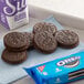 A group of Nabisco Oreo cookies on a blue napkin next to a package of Nabisco Oreo cookies.