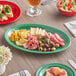 An oval green melamine platter on a table with food.