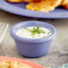 A plate of food with a purple bowl of white sauce and green garnish.