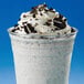 A white drink with whipped cream and black Oreo cookie crumbs on top.