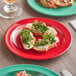 A close-up of food on a red Acopa Foundations melamine plate with a glass of wine on a table.