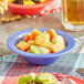 A table with Acopa Foundations purple melamine fruit dishes filled with fruit salad.