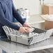 A man stacking a gray Lavex small industrial tote on a counter.