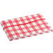 A red and white checkered Choice vinyl table cover on a table with an umbrella opening.