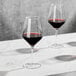 a glass of red wine on a white table