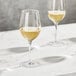 Three Della Luce Maia white wine glasses on a marble table.