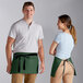 A man and woman wearing Choice hunter green waist aprons with black webbing.
