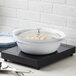 A white bowl with food in a white ceramic pot on a Spring USA induction warmer.