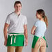 A man and woman wearing green aprons.