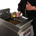 A person using a Vito Fryfilter FT 440 Fryer Oil Monitor on a fryer.