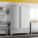 A large stainless steel solid door reach-in freezer with double doors and caster wheels.
