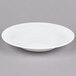 An Arcoroc white glass soup/pasta bowl on a gray surface.