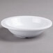 A Carlisle white melamine grapefruit bowl on a gray surface.