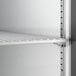 A close-up view of an adjustable wire shelf inside a stainless steel reach-in refrigerator.