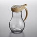 A clear glass Vollrath syrup dispenser with a tan plastic lid and handle.