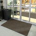A brown Lavex Dilour entrance mat in front of a glass door.