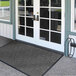 A Lavex gray chevron pattern entrance mat on the front of a building.