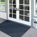 A blue Lavex Chevron Rib entrance mat on a white door.