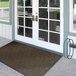 A brown Lavex Chevron Rib entrance mat with double doors.