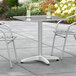 A Lancaster Table & Seating chrome square outdoor table with two glasses on it.