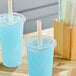 A blue drink in a plastic cup with a Choice multicolor striped boba straw.