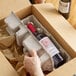 A hand holding a Lavex Molded Fiber stackable wine shipper tray with a bottle of wine inside.