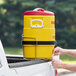 A man using a yellow Igloo insulated beverage dispenser on a metal rack.