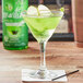A glass of green liquid with a green apple slice on the rim.