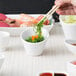 A person holding chopsticks over a bowl of food.