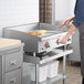 A woman using an APW Wyott electric countertop griddle to cook food.