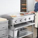 A woman in an apron using an APW Wyott electric countertop griddle to cook food in a commercial kitchen.