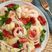 A plate of pasta with shrimp, spinach, and Del Destino sundried tomato halves.